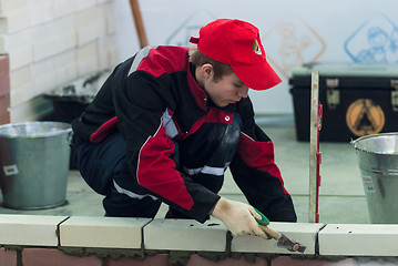 Image showing Young bricklayer performs a task of competition