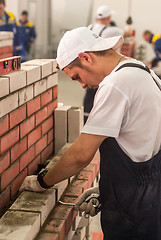 Image showing Young bricklayer performs a task of competition