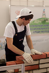 Image showing Young bricklayer performs a task of competition