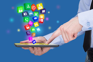 Image showing Businessman holding a tablet pc with mobile applications icons on virtual screen . Internet and business concept.