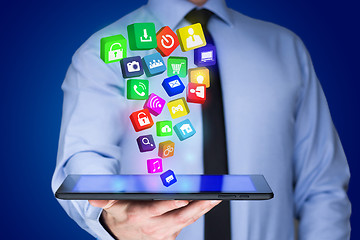 Image showing Businessman holding a tablet pc with mobile applications icons on virtual screen . Internet and business concept.