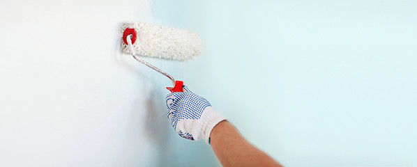 Image showing close up of male in gloves painting wall