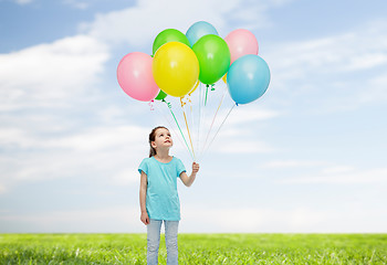 Image showing girl looking up with bunch of helium balloons