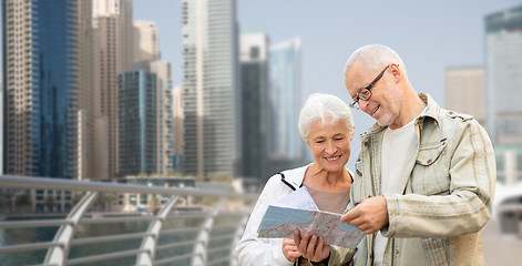 Image showing happy senior couple with map over dubai city