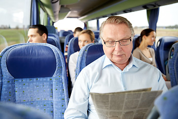 Image showing happy senior man reading newspaper in travel bus