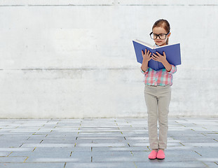 Image showing happy little girl in eyeglasses reading book