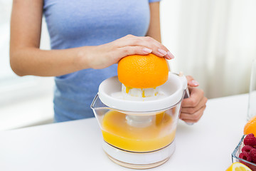 Image showing close up of woman squeezing orange juice at home