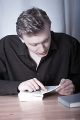 Image showing The young man bent over the book