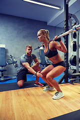 Image showing man and woman with bar flexing muscles in gym