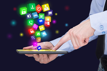 Image showing Businessman holding a tablet pc with mobile applications icons on virtual screen . Internet and business concept.