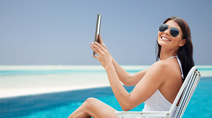 Image showing smiling woman with tablet pc sunbathing on beach