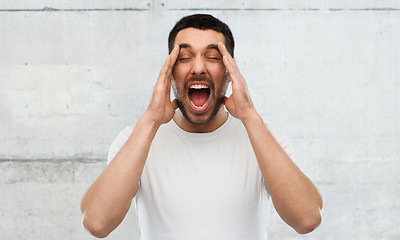 Image showing crazy shouting man in t-shirt over gray wall