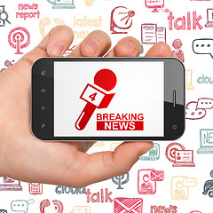 Image showing News concept: Hand Holding Smartphone with Breaking News And Microphone on display
