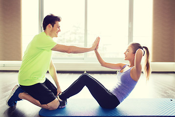 Image showing woman with personal trainer doing sit ups in gym