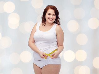 Image showing happy young plus size woman with measuring tape