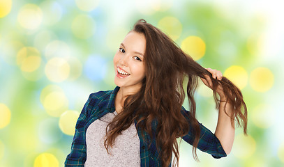 Image showing happy teenage girl holding strand of her hair