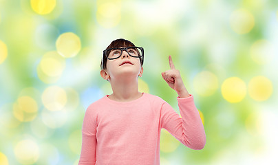 Image showing happy little girl in eyeglasses pointing finger up