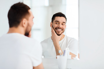 Image showing happy young man looking to mirror at home bathroom