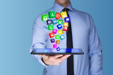 Image showing Businessman holding a tablet pc with mobile applications icons on virtual screen . Internet and business concept.