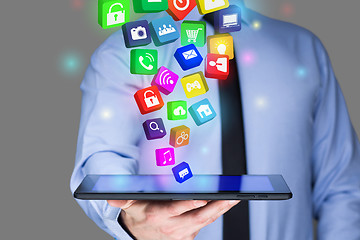 Image showing Businessman holding a tablet pc with mobile applications icons on virtual screen . Internet and business concept.