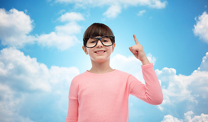 Image showing happy little girl in eyeglasses pointing finger up