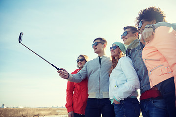 Image showing smiling friends taking selfie with smartphone