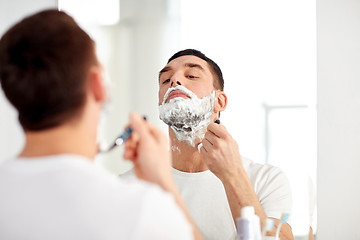 Image showing man shaving beard with razor blade at bathroom