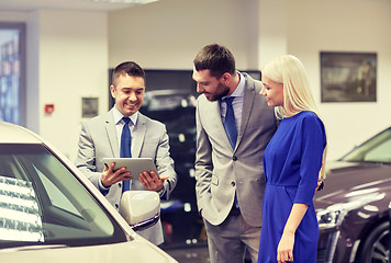 Image showing happy couple with car dealer in auto show or salon