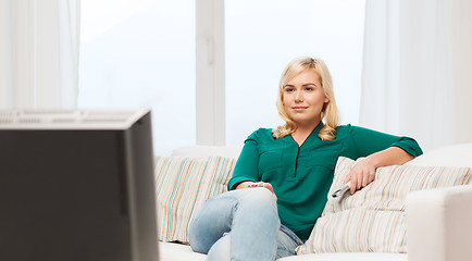 Image showing smiling woman with remote watching tv at home