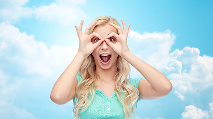 Image showing young woman looking through finger glasses