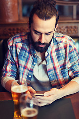 Image showing man with smartphone drinking beer at bar