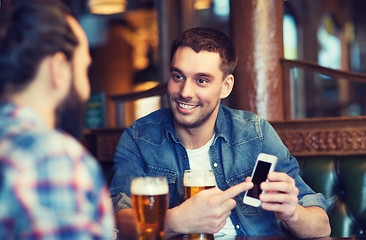 Image showing male friends with smartphone drinking beer at bar