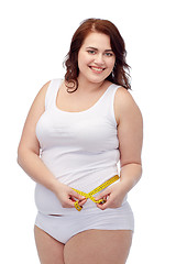 Image showing happy young plus size woman with measuring tape