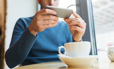 Image showing close up of man with smartphones at cafe