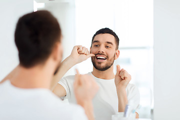 Image showing man with dental floss cleaning teeth at bathroom