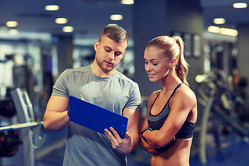 Image showing smiling young woman with personal trainer in gym