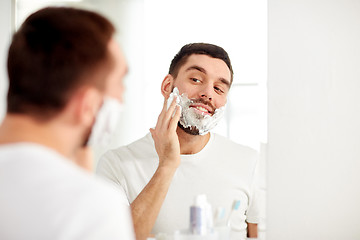 Image showing happy man applying shaving foam at bathroom mirror