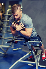 Image showing young man flexing back muscles on bench in gym