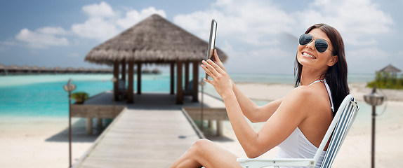 Image showing smiling woman with tablet pc sunbathing on beach