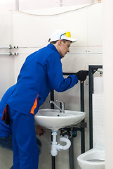 Image showing Young plumber installs equipment for bathroom