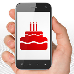 Image showing Entertainment, concept: Hand Holding Smartphone with Cake on display