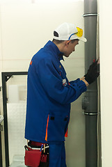 Image showing Young plumber installs equipment for bathroom