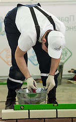 Image showing Young bricklayer performs a task of competition