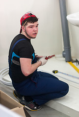 Image showing Young plumber installs equipment for bathroom