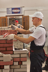 Image showing Young bricklayer performs a task of competition