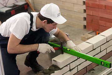 Image showing Young bricklayer performs a task of competition