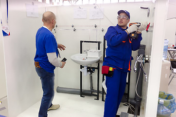 Image showing Young plumber installs equipment for bathroom