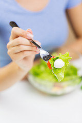 Image showing close up of young woman eating salad at home