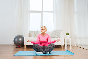 Image showing happy woman stretching leg on mat at home