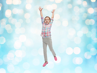 Image showing happy little girl jumping in air over blue lights